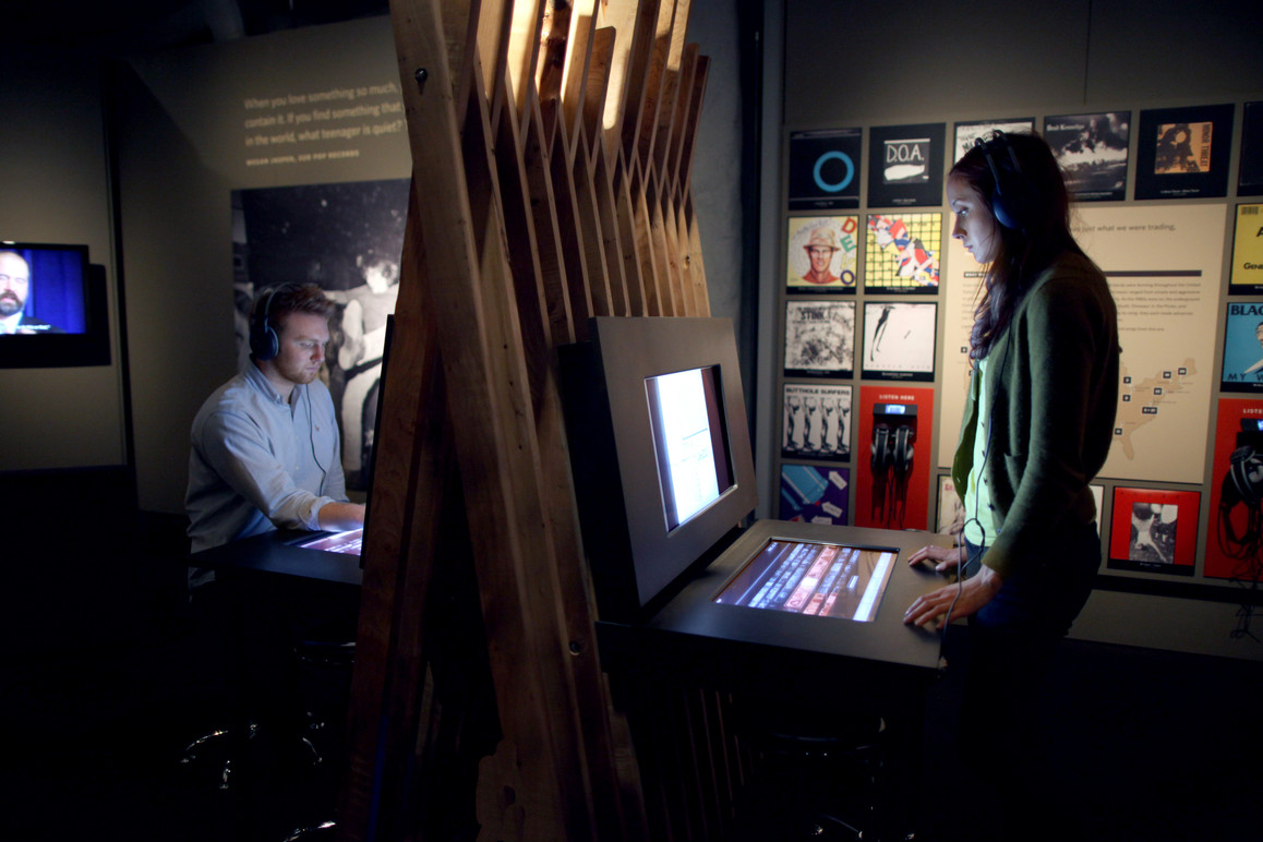 Visitors using the first (of three) interactive touchtable stations to explore an extensive collection of media and oral histories not seen elsewhere in the exhibition.